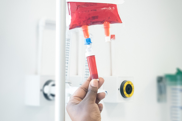 a hand adjusting a red drip