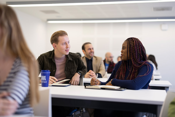 Two students sat at a desk talking